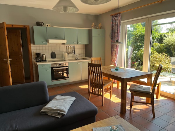 Une cuisine moderne avec des meubles de couleur bleu clair, une table à manger avec des chaises et un canapé avec une couverture.