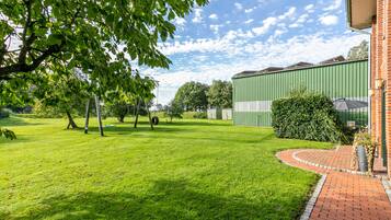 A green field with a brick pathway leading to a building with a green roof.