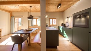 Una cocina moderna con horno integrado y un comedor con mesa y banco de madera.
