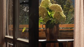 Una ventana con vistas a montañas y un florero con flores.