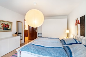 Un dormitorio con cama, mesita de noche, lámpara y una lámpara colgante grande.