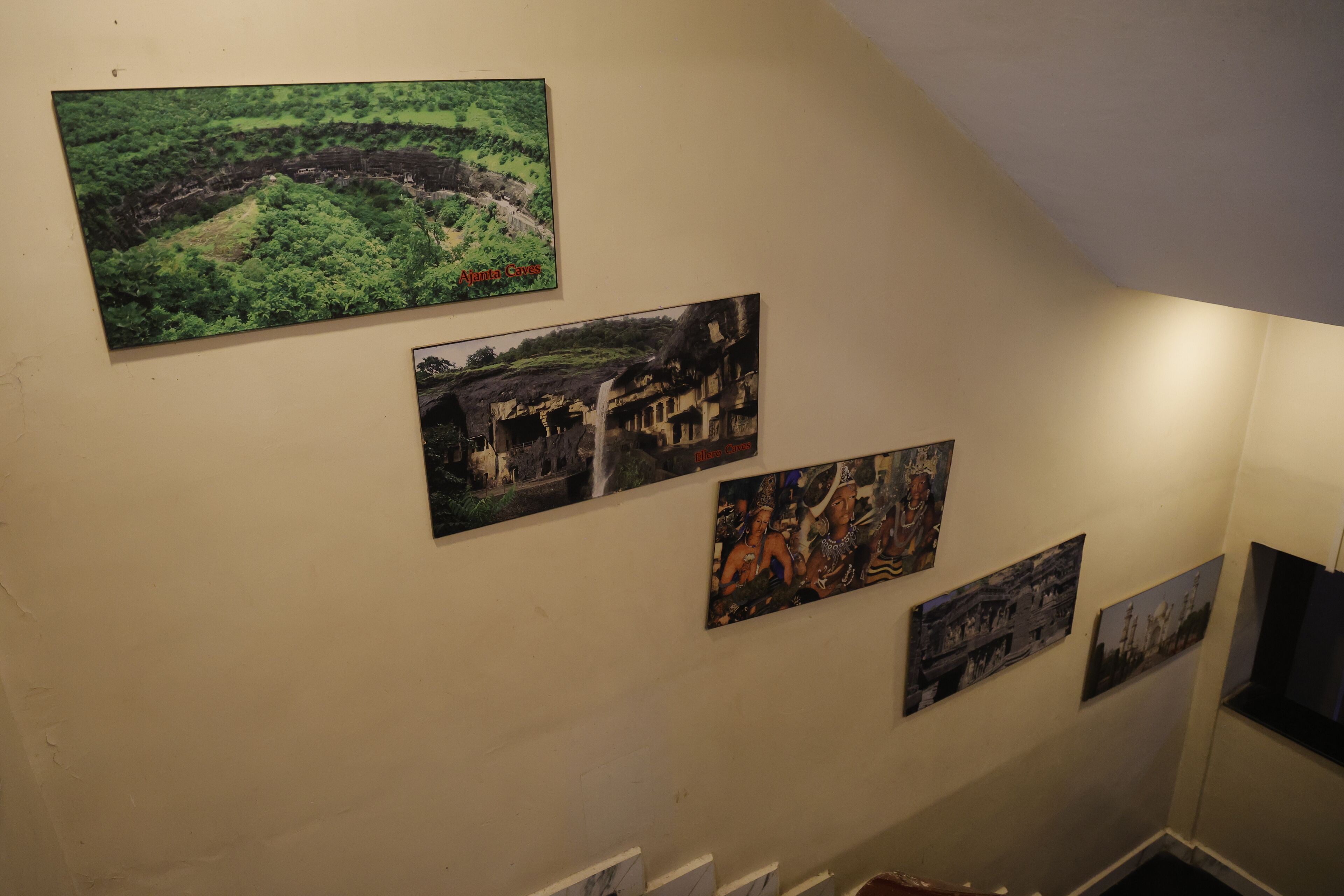 Eine Wand mit mehreren gerahmten Fotografien, die verschiedene Landschaften und Gebäude zeigen.