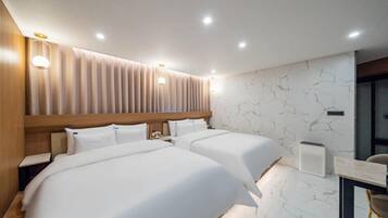 A modern hotel room with two beds, a wooden headboard, a marble-patterned wall, and a desk with a chair.
