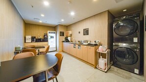 Una habitación de hotel compacta con kitchenette, comedor y lavadora-secadora.