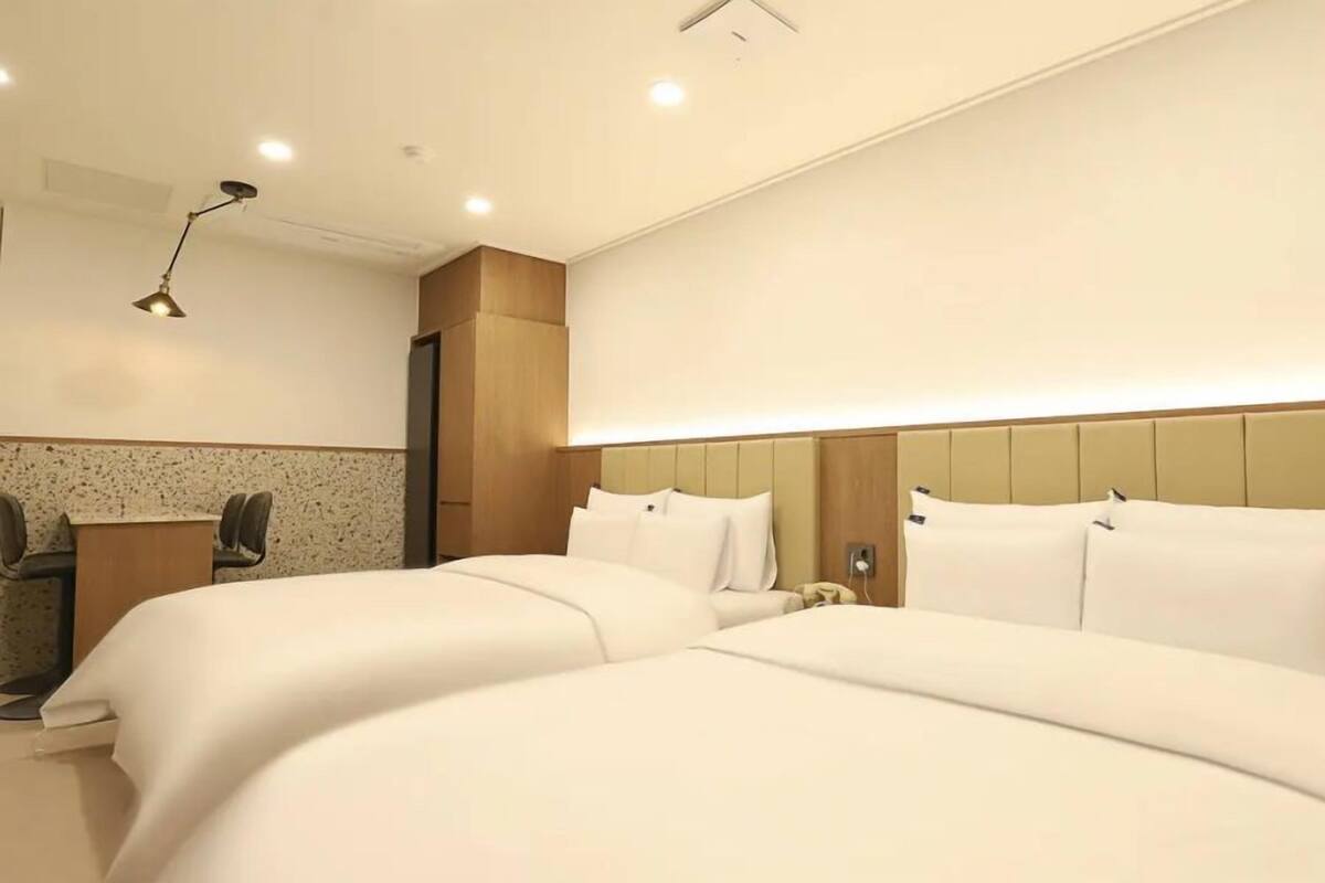 A hotel room with two beds, a desk, and a chair.