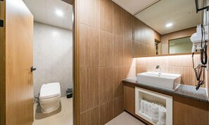Un baño moderno con tocador de madera, un lavabo blanco y un inodoro.