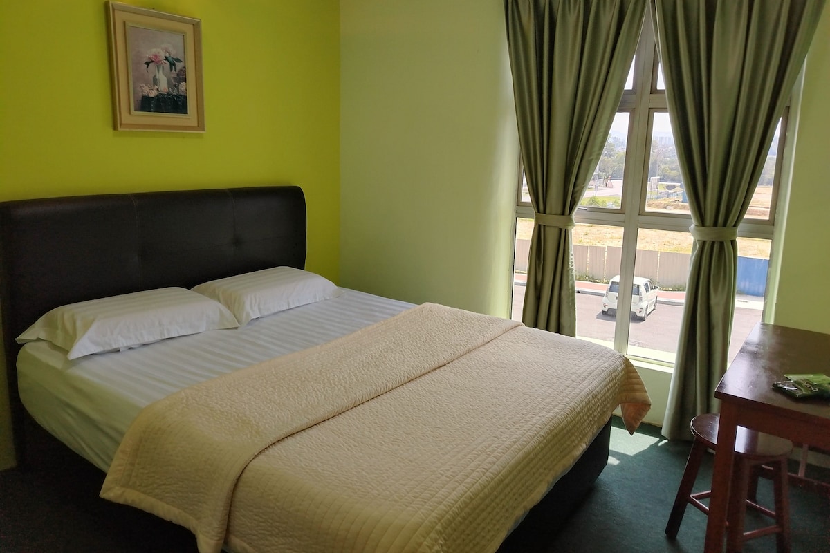 Una habitación de hotel con cama, un cuadro en la pared y una ventana con cortinas.