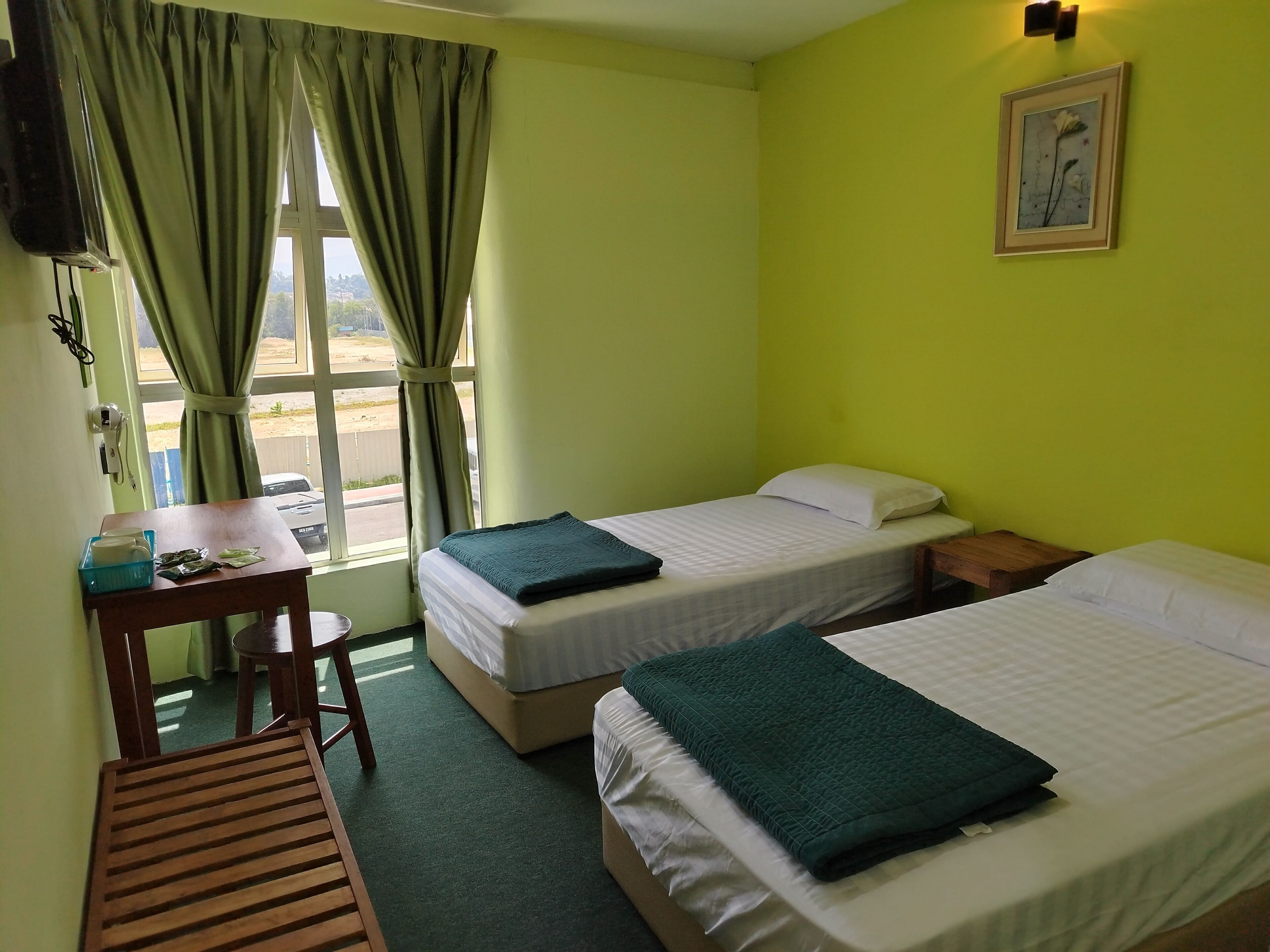 A room with two beds, a desk, a chair, a window with curtains, and a painting on the wall.