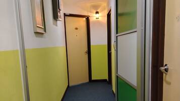 A narrow hallway with a blue carpet, yellow and white walls, and doors with green panels.