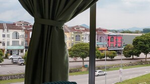 A bed with a green quilt, a window with a view of buildings and a street. - Hotel O Seremban Near SnowLim Wonderland Formerly M&N Hotel (Seremban)