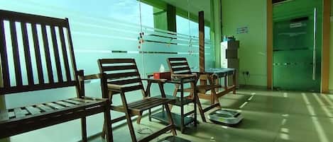Una habitación con sillas y mesas de madera, un separador de vidrio y una pared verde.