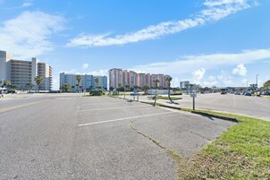 A parking lot with multiple rows of parking spaces, a stop sign, and a building with multiple floors in the background.