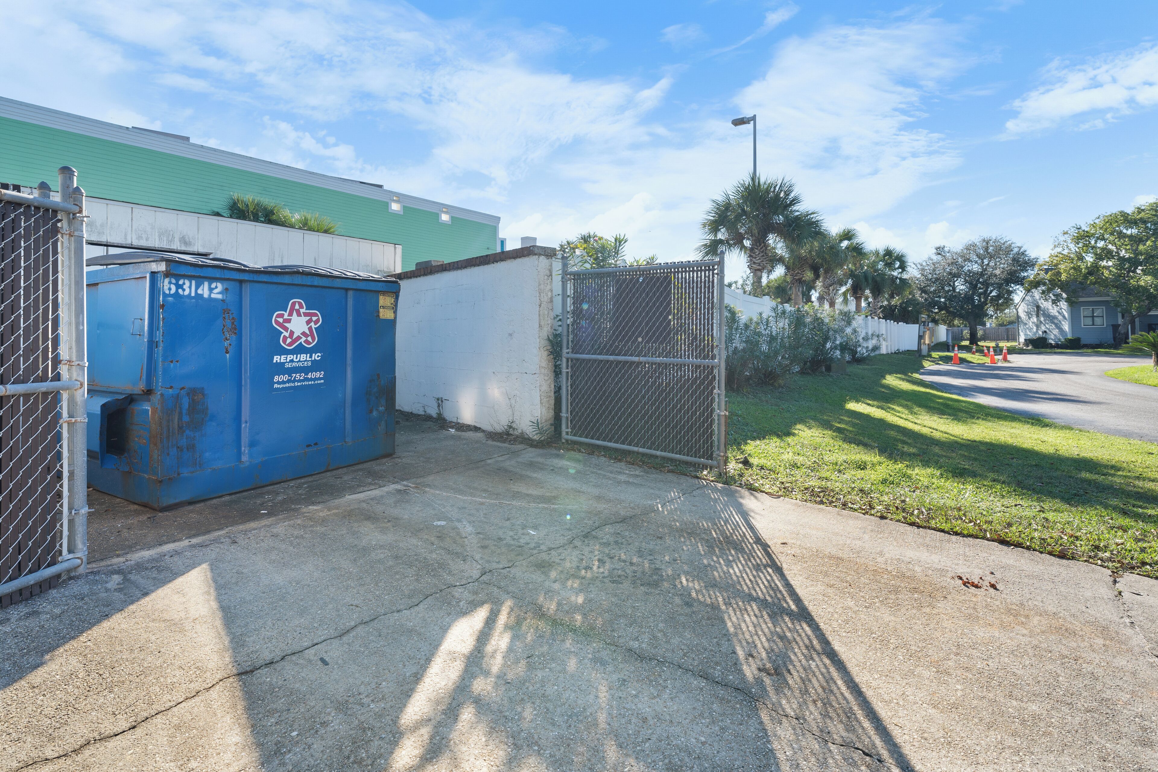 A gated area with a blue dumpster labeled "Republic Services" and a chain-link fence.