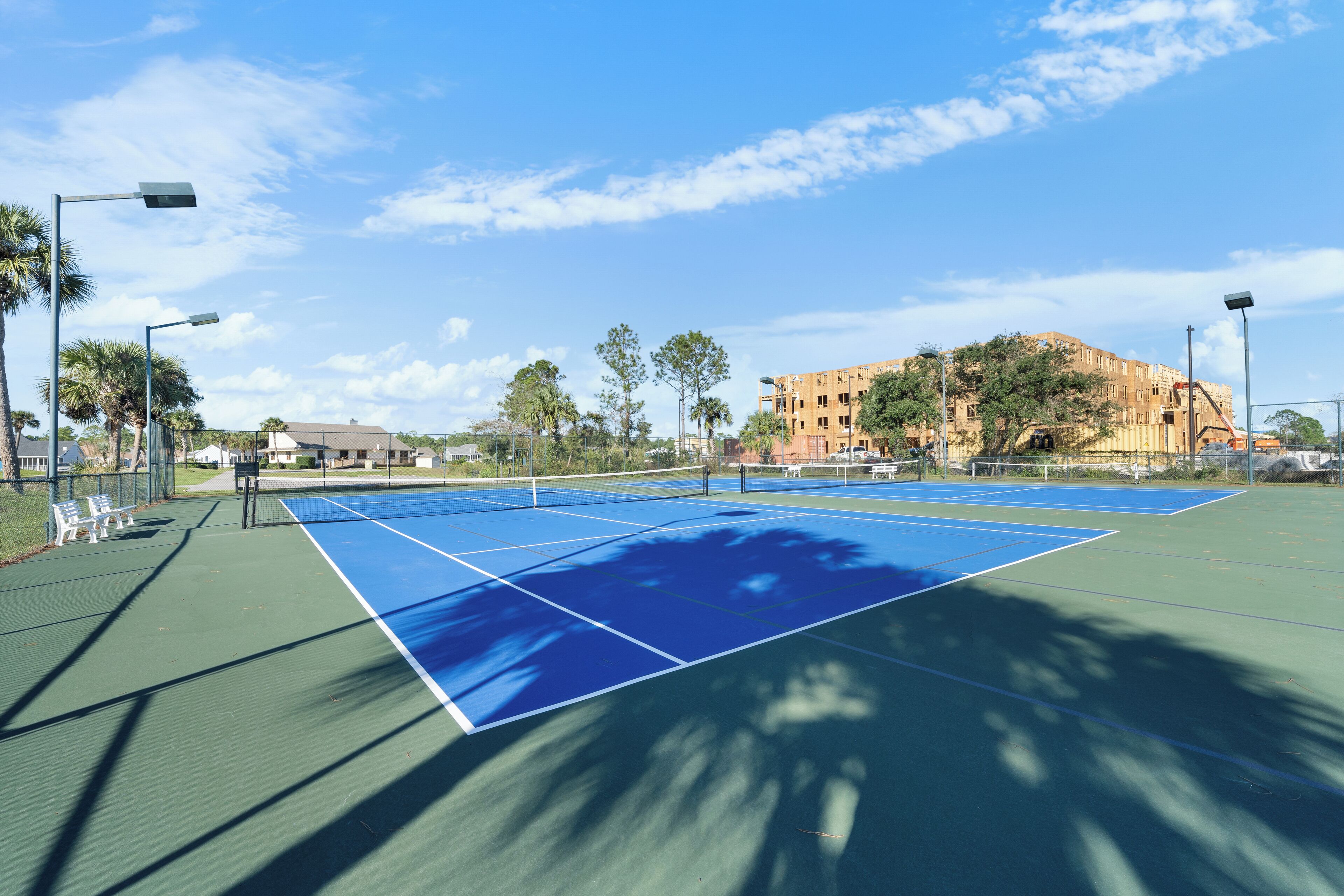 Cancha de tenis con red, rodeada de árboles y edificios.