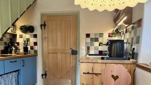 Eine Küche mit Holztür, Kaffeemaschine und gefliestem Rücksprung.