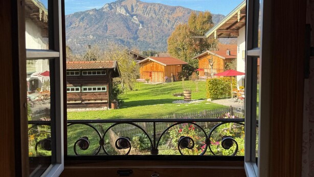 Ein Zimmer mit großem Fenster mit Blick auf einen Berg und ein Dorf.