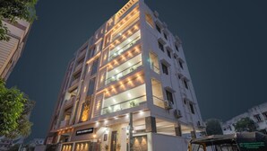 Un hôtel à plusieurs étages au design moderne, doté de balcons et d’une entrée bien éclairée.