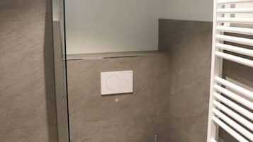Une salle de bain moderne avec une douche à parois de verre, des toilettes blanches et un porte-serviettes.