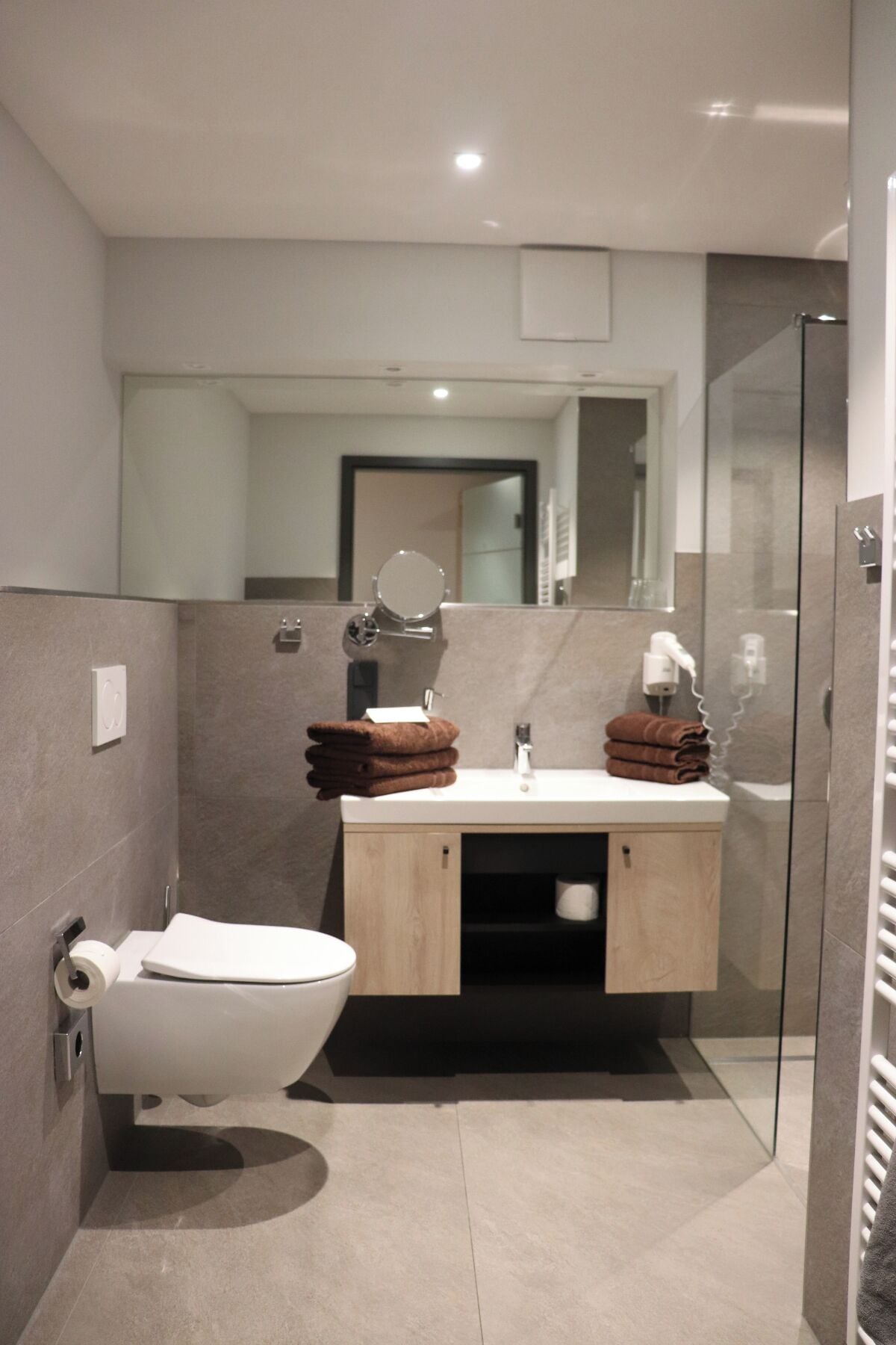 Un baño moderno con inodoro, lavamanos y cabina de ducha de vidrio.