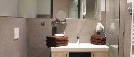 A modern bathroom with a toilet, sink, and glass shower enclosure.
