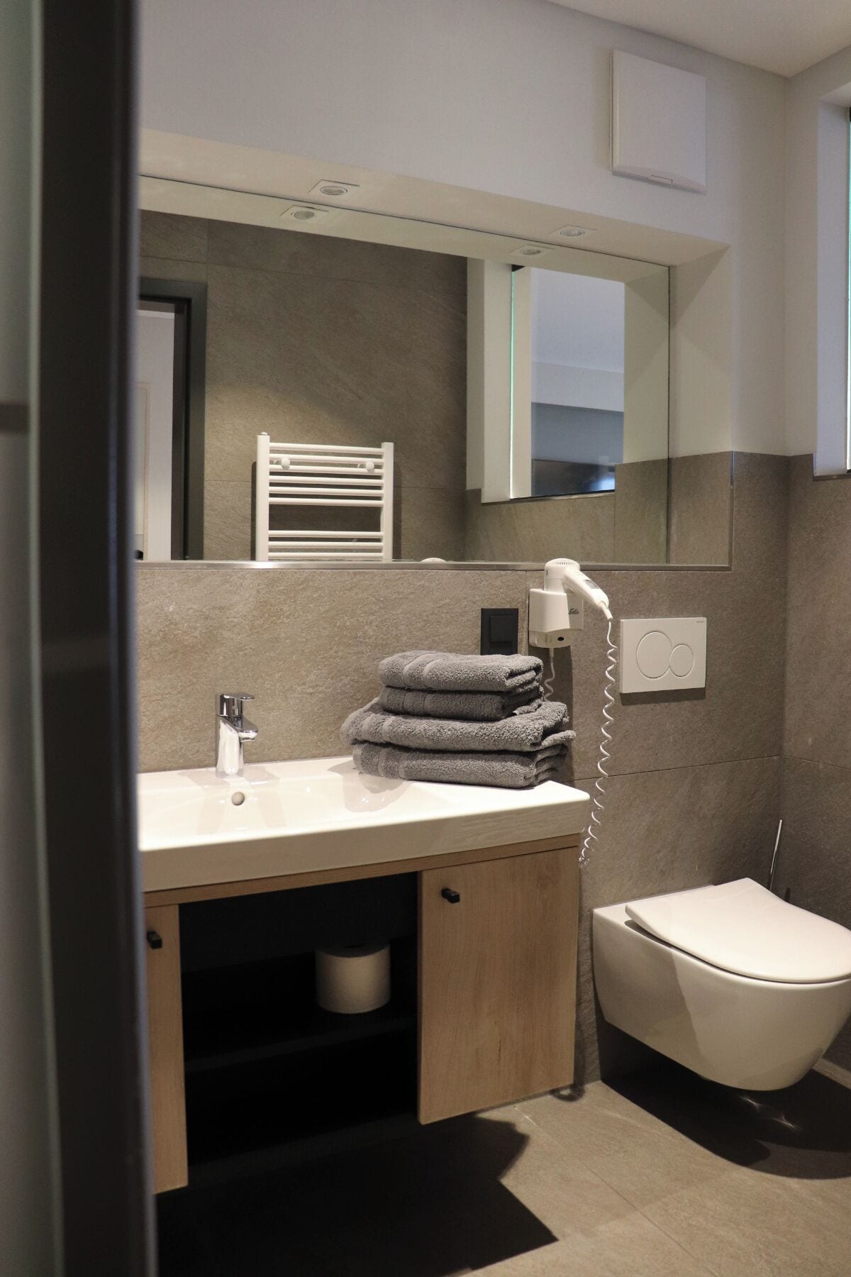 Un baño moderno con lavamanos, toallero, inodoro y espejo.