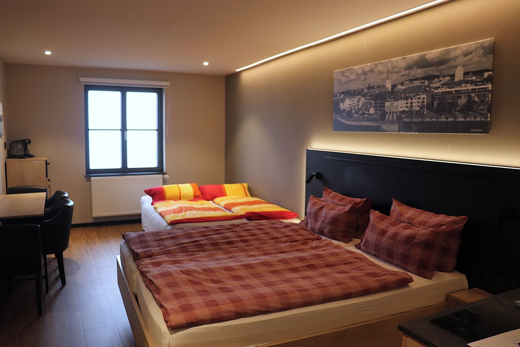 A bedroom with a large bed, a desk, and a window.