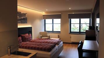 Un dormitorio moderno con cama, mesita de noche, silla y escritorio.