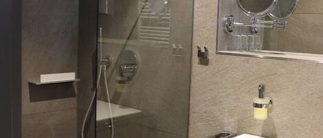 Un baño moderno con ducha de vidrio, un armario de madera y un espejo sobre el lavabo.