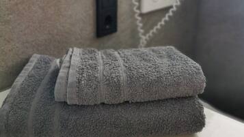 A neatly folded gray towel on a white bathroom counter next to a wall-mounted phone.