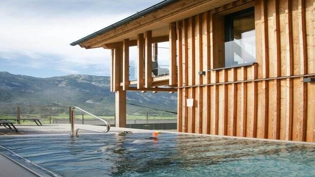 Edificio de madera con piscina y vistas a las montañas.