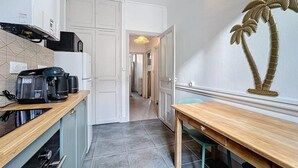 Une cuisine moderne dotée d’un plan de travail en bois, d’une machine à café et d’un four encastré. On y trouve également un coin repas avec une table et des chaises en bois.