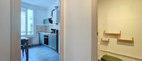 A narrow hallway leading to a kitchen with a dining area and a toilet.