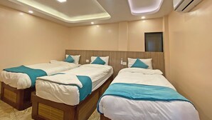 Habitación de hotel con tres camas individuales, cada una con cabecero de madera y ropa de cama color turquesa.