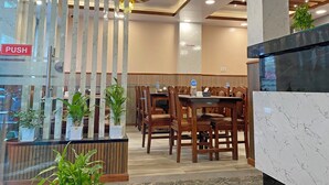 Vestíbulo de hotel con una mesa de recepción, sillas de madera, un cartel de 'EMPUJAR' y un letrero de 'NO FUMAR'.