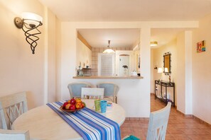 A cozy dining area for two, featuring a round table and a bowl of fresh fruit.