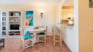A dining area with a round table, chairs, and a bookshelf. - The Torrent's Observer Holiday Home - Apartment (Cala Pi, Illes Balears)