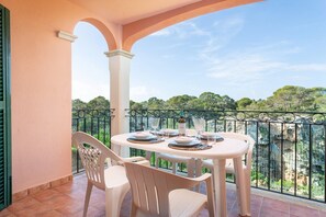 Enjoy al fresco dining on the balcony with a table set for two, overlooking a serene landscape of trees and rocky terrain.