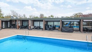 A swimming pool with a covered patio area, outdoor seating, and a slide. - 4 Person Holiday Home in Glesborg (Glesborg)