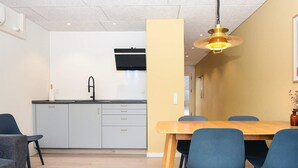 A modern kitchen with a sink, cabinets, and a dining area with a table and chairs. - 4 Person Holiday Home in Glesborg (Glesborg)