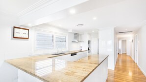 Una cocina moderna con una isla grande, armarios blancos y suelo de madera.
