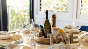Una mesa dispuesta para una comida, con copas de vino, platos y una botella de vino.