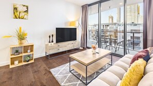 Una sala de estar moderna con un televisor de pantalla plana, una mesa de centro de madera y un sofá.