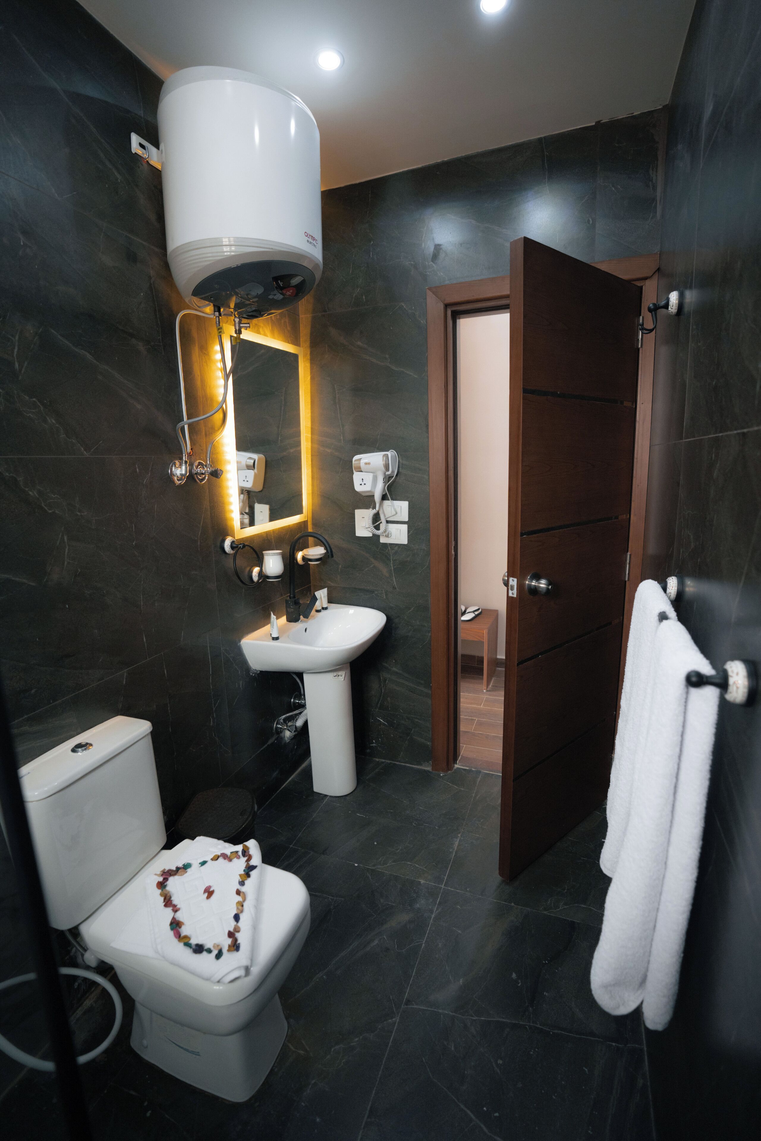 Ein modernes Badezimmer mit Toilette, Waschbecken und einem großen Spiegel.