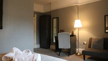 Una habitación de hotel con una cama, un escritorio, una silla, una lámpara y un sofá.