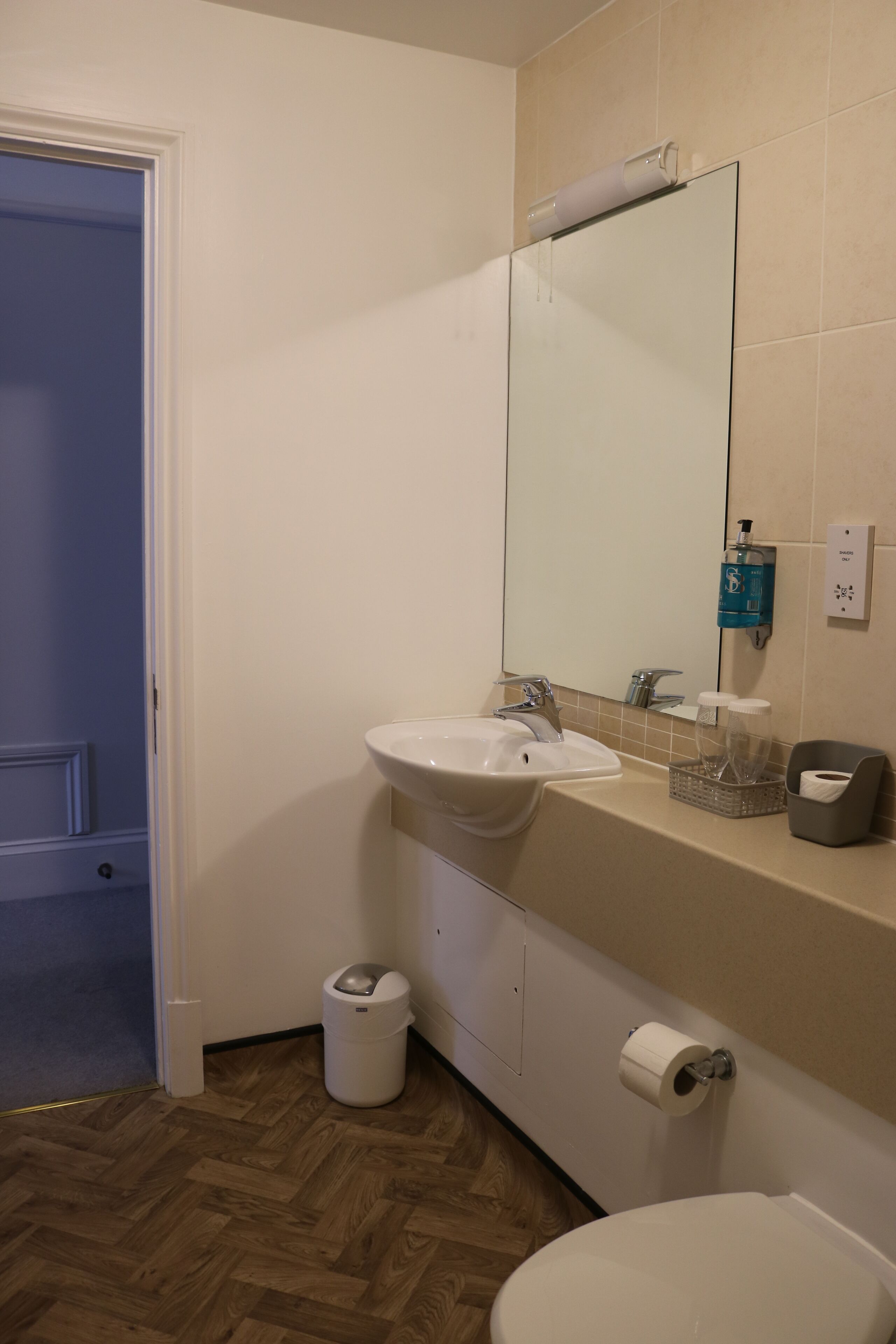 Ein Badezimmer mit Waschbecken, Spiegel, Toilette und Mülleimer.