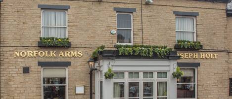 Un edificio de ladrillo con dos carteles que dicen "NORFOLK ARMS" y "SEPH HOLT".