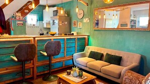 Een gezellige woonkamer met een bank, twee stoelen, een salontafel en een bar met krukken.