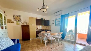 A compact living space with a dining area, kitchenette, and a balcony.