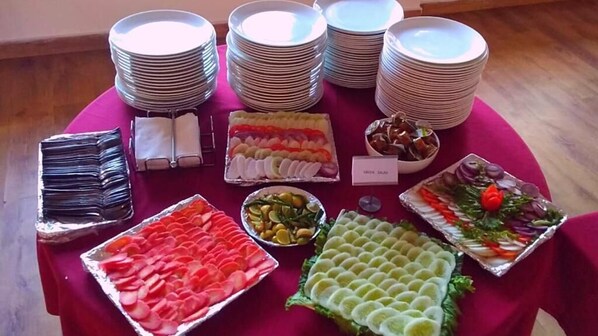 A table with various food items and stacked plates, likely for a buffet or catering event.