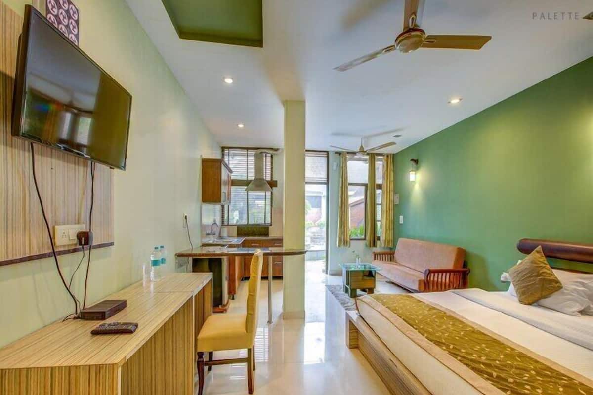 A modern hotel room with a bed, a desk, a chair, a TV, and a ceiling fan.